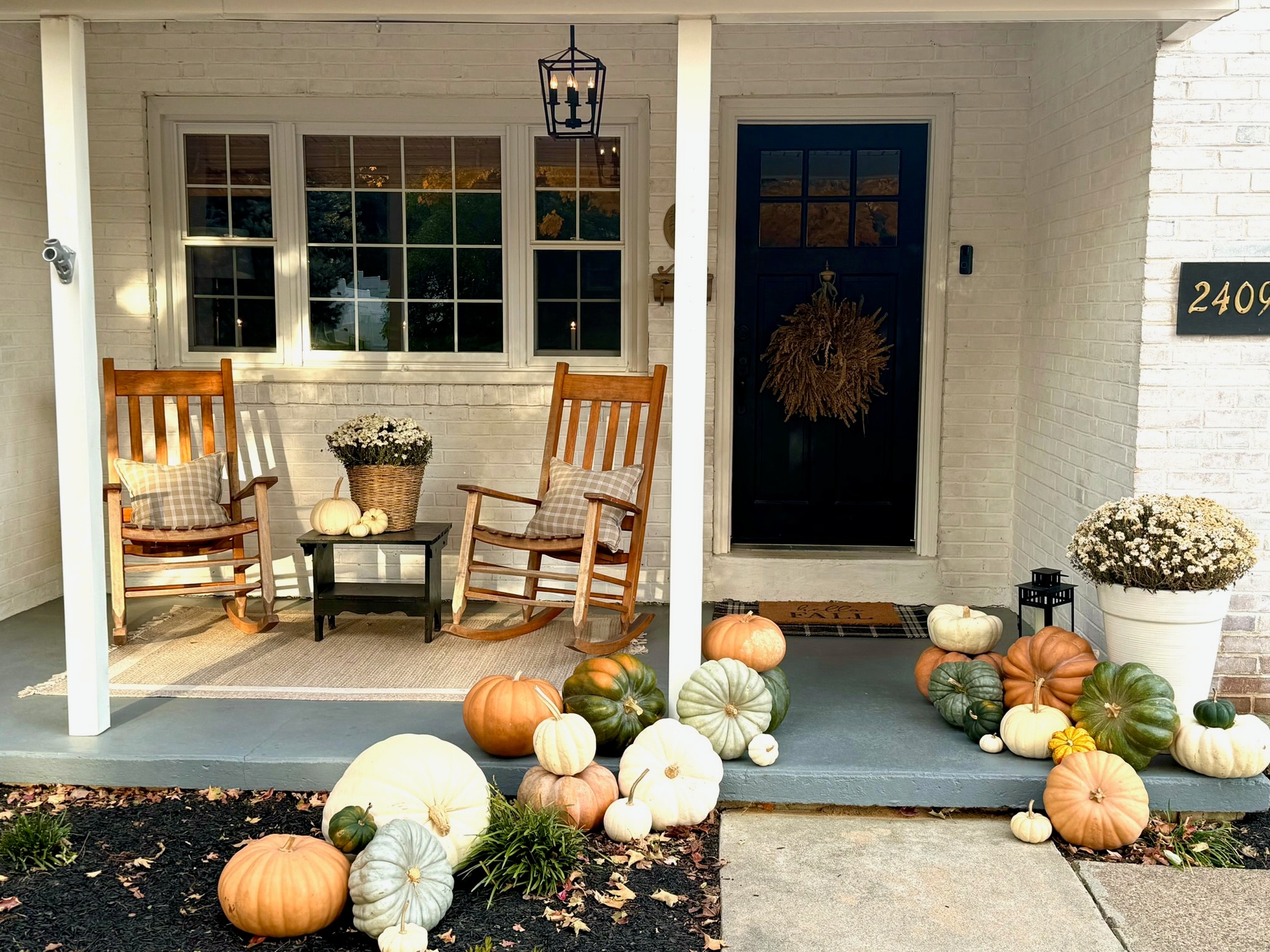 White brick porch with rocking chairs and pumpkins